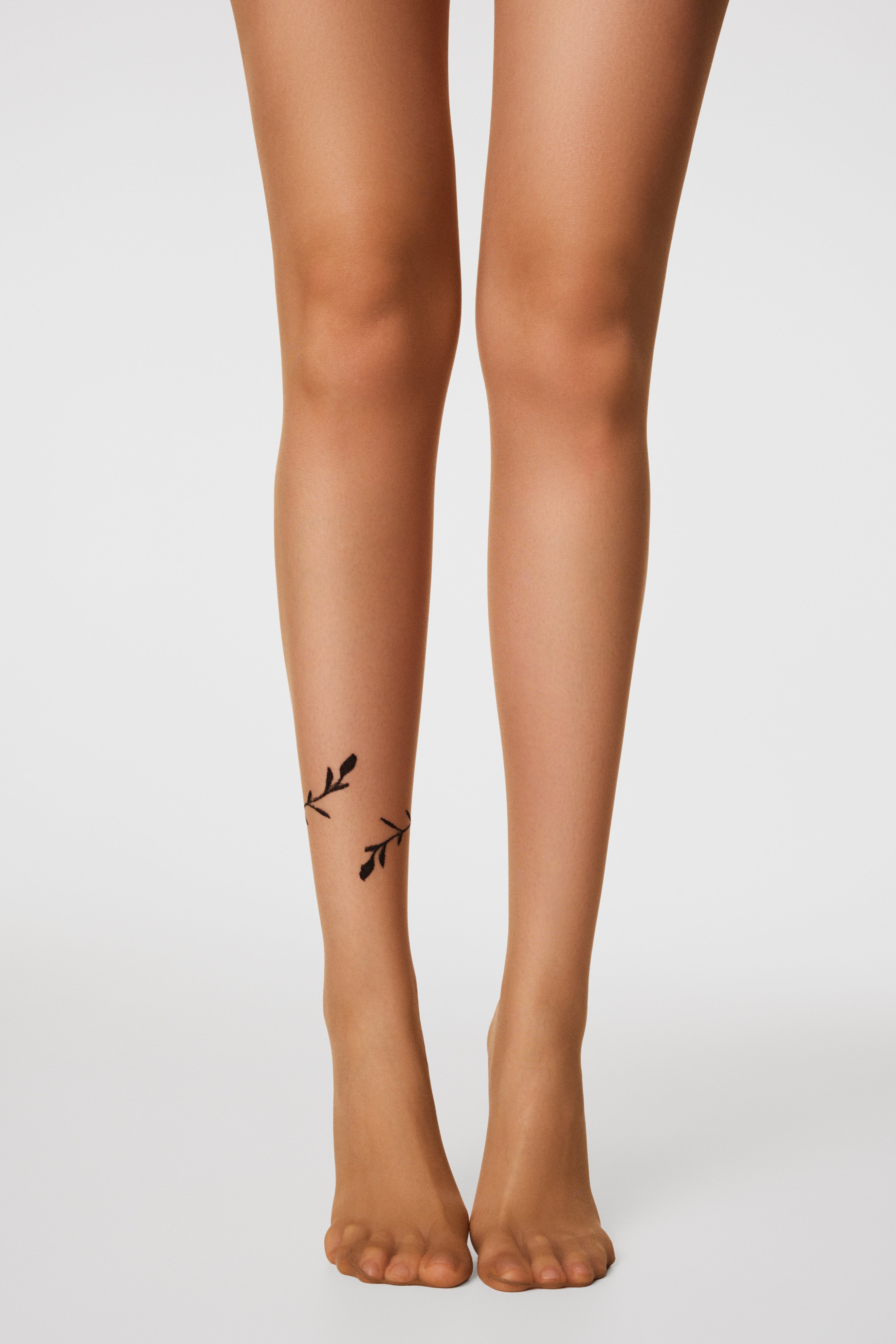Legs wearing sheer stockings with a subtle design on a plain background