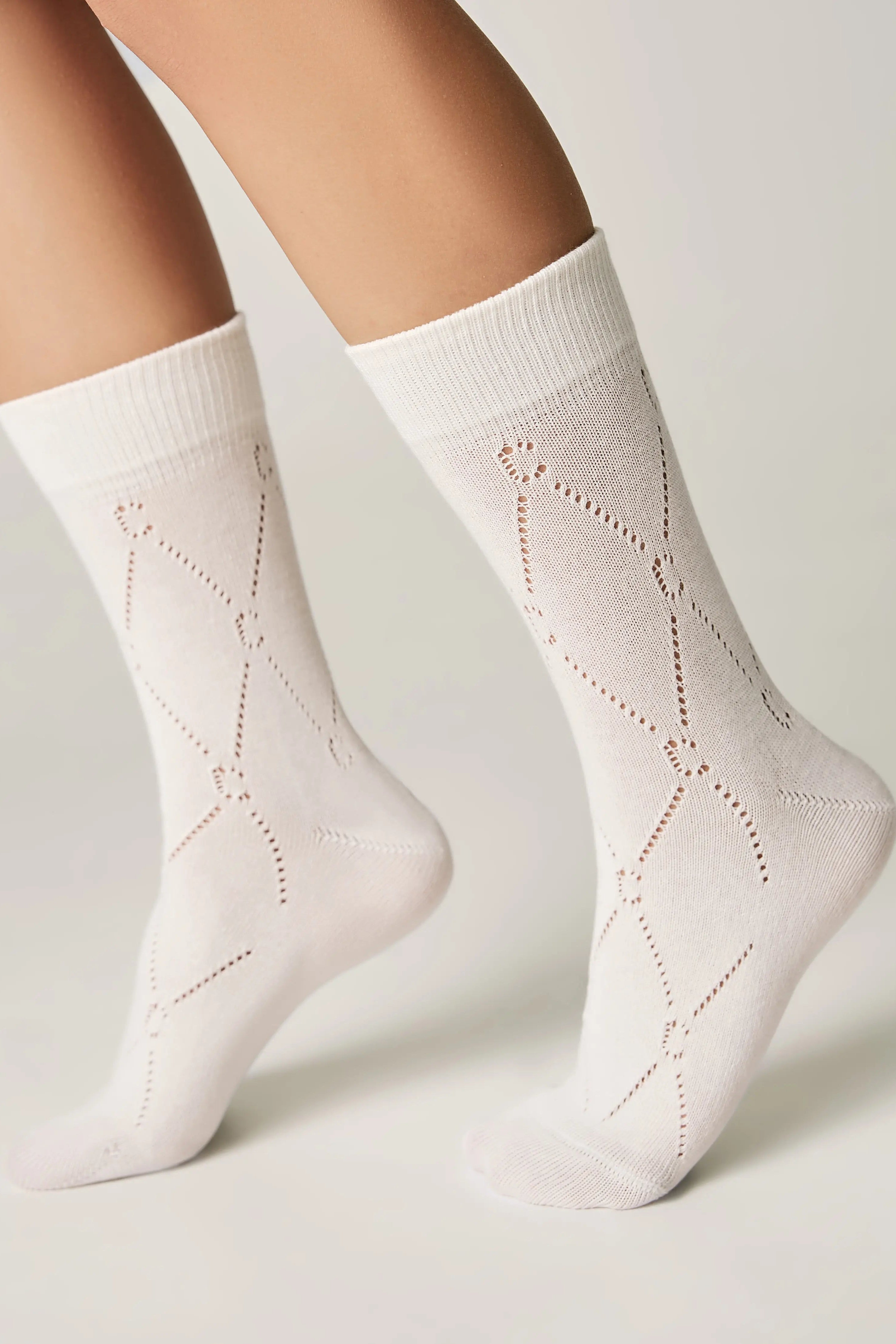 White socks with a subtle pattern worn by a person on a light gray background #color_milk