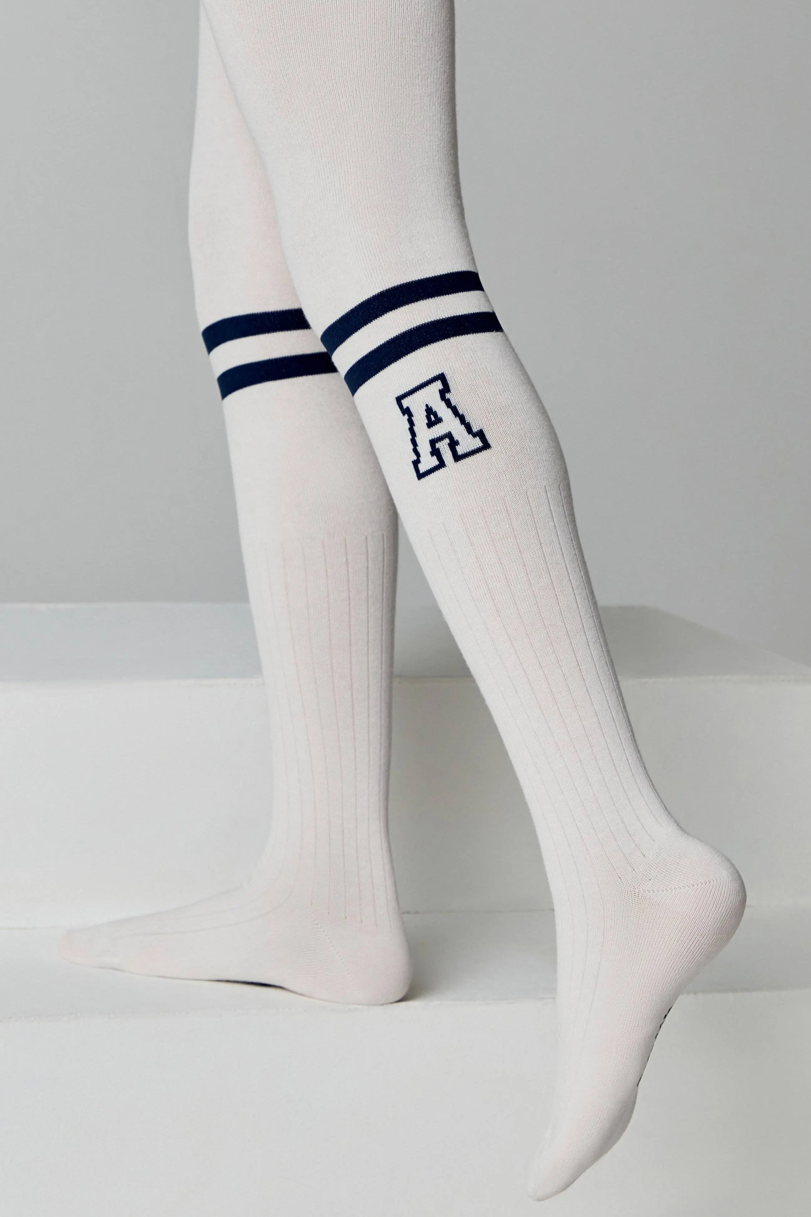 White knee-high socks with blue stripes and a letter 'A' on a light gray background