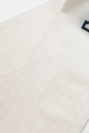 Close-up of a white fabric with a subtle pattern on a wooden surface