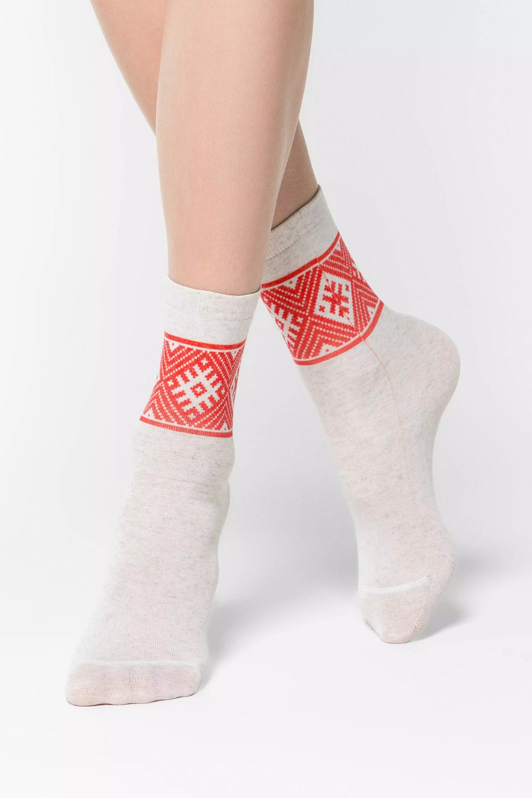 White socks with red geometric patterns worn by a person on a white background