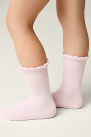 Pink socks with scalloped edges worn by a child on a light background #color_light-pink