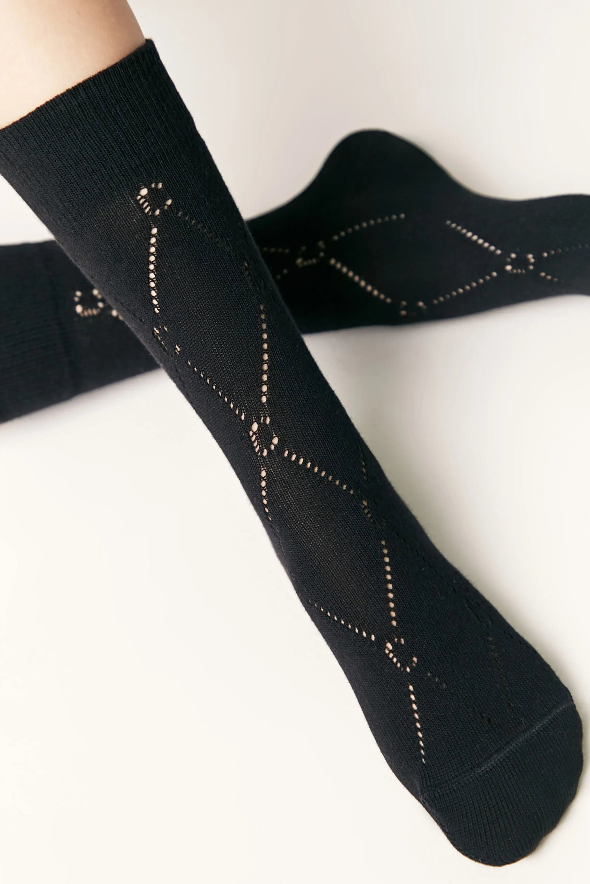 Black socks with gold patterns worn by a person on a white background #color_black