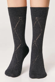 Dark gray socks with diamond pattern worn by a person on a light gray background #color_dark-gray