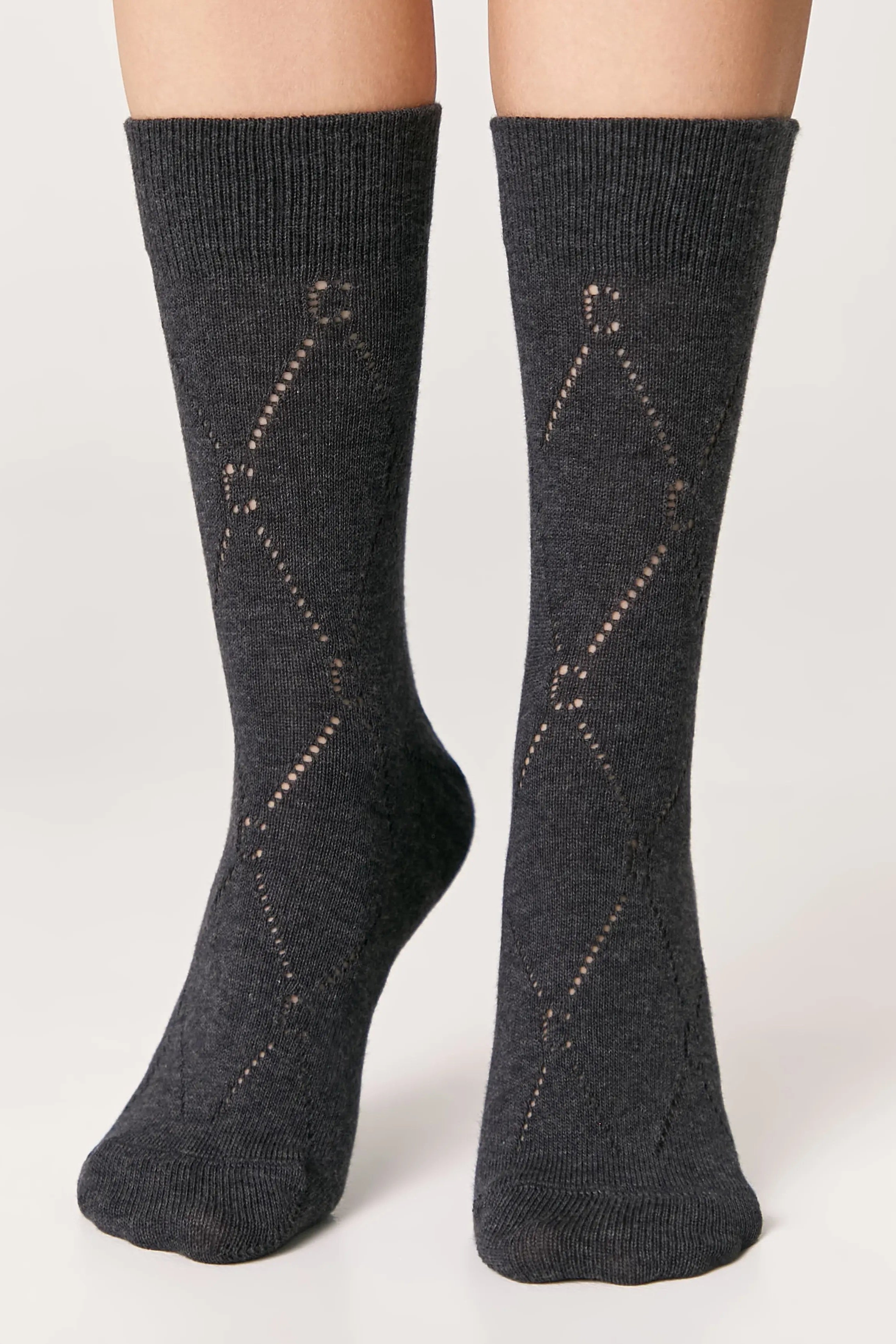Dark gray socks with diamond pattern worn by a person on a light gray background #color_dark-gray