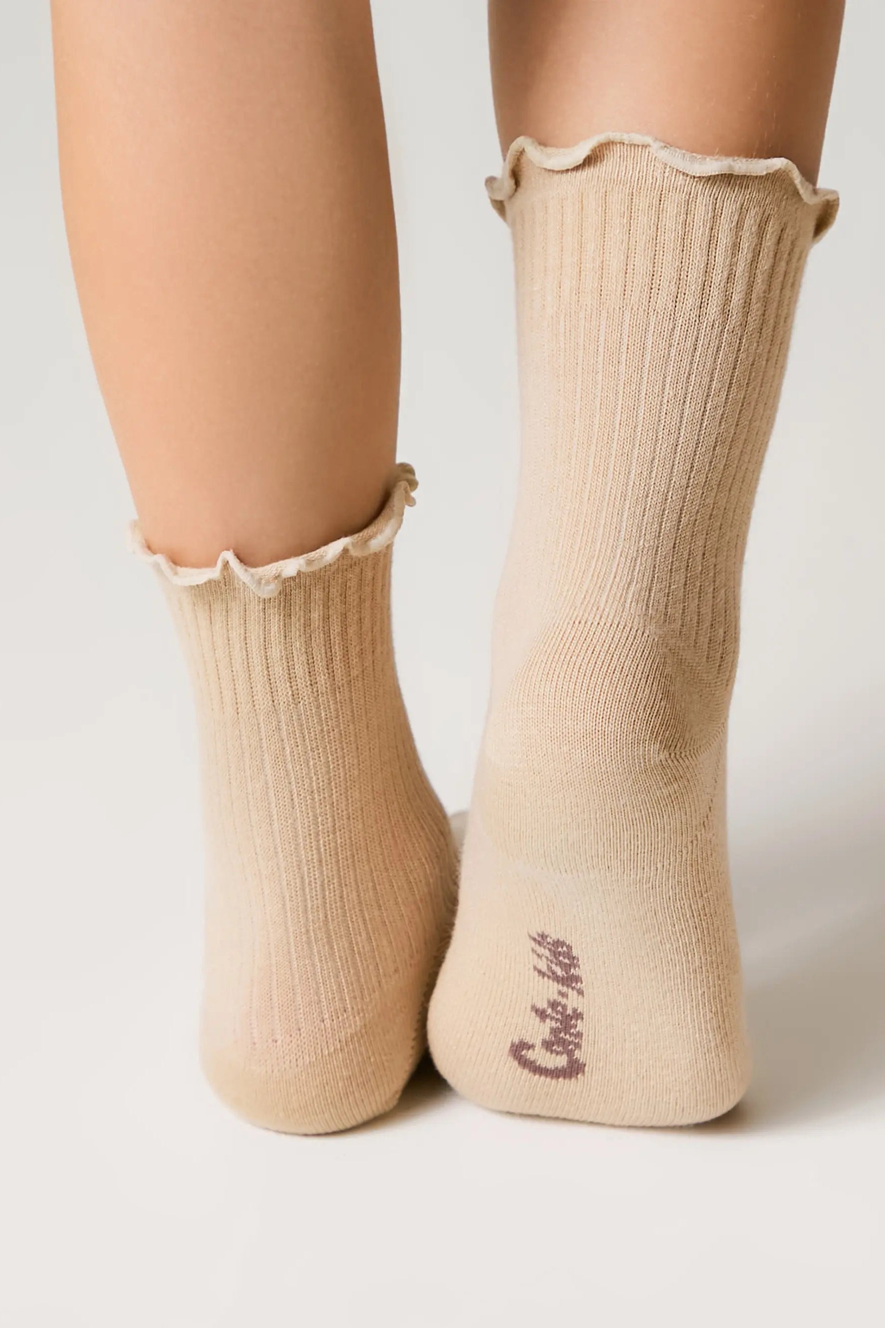 Beige socks with ruffled top worn by a person on a light background #color_beige