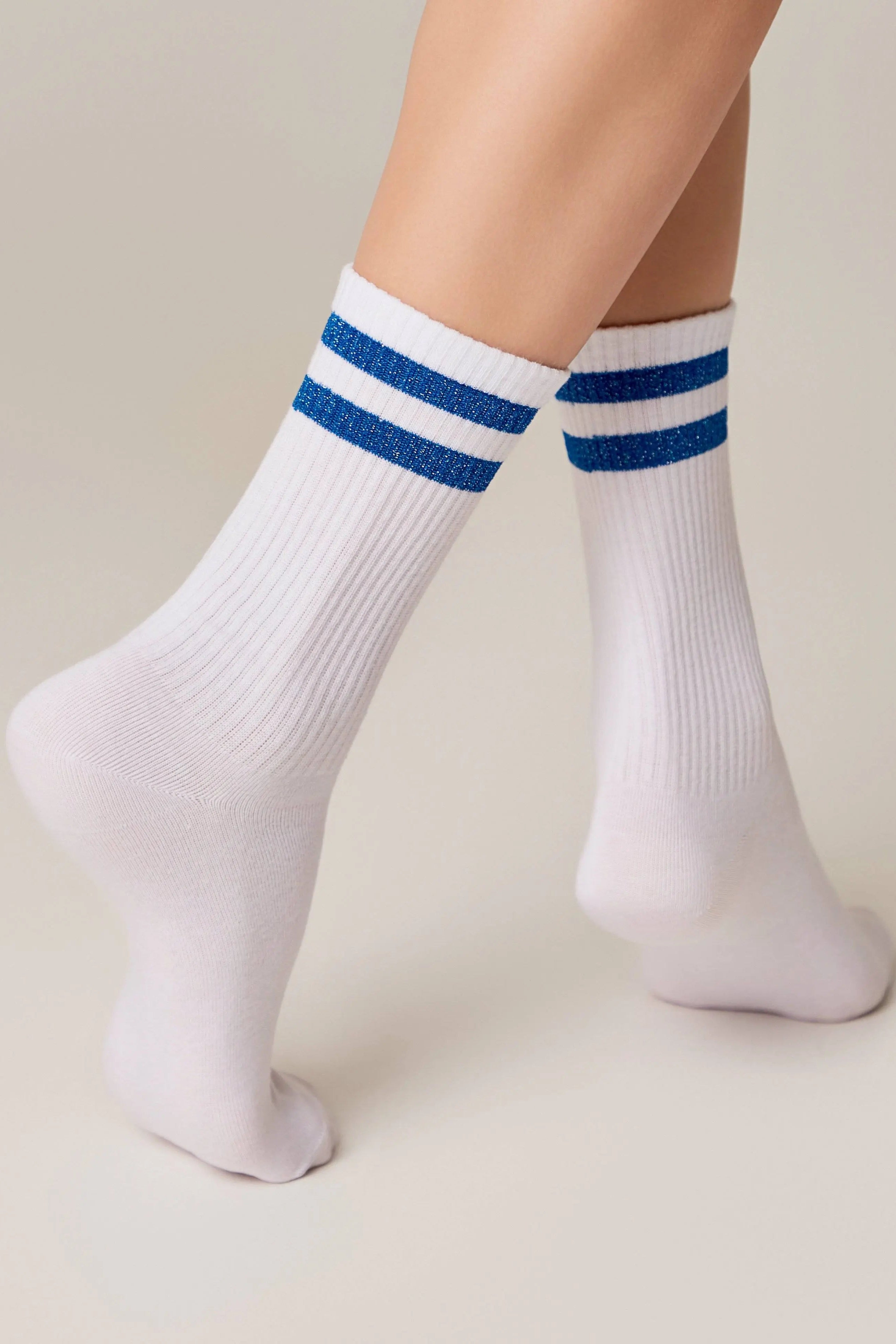 White socks with blue stripes worn by a person on a beige background #color_blue