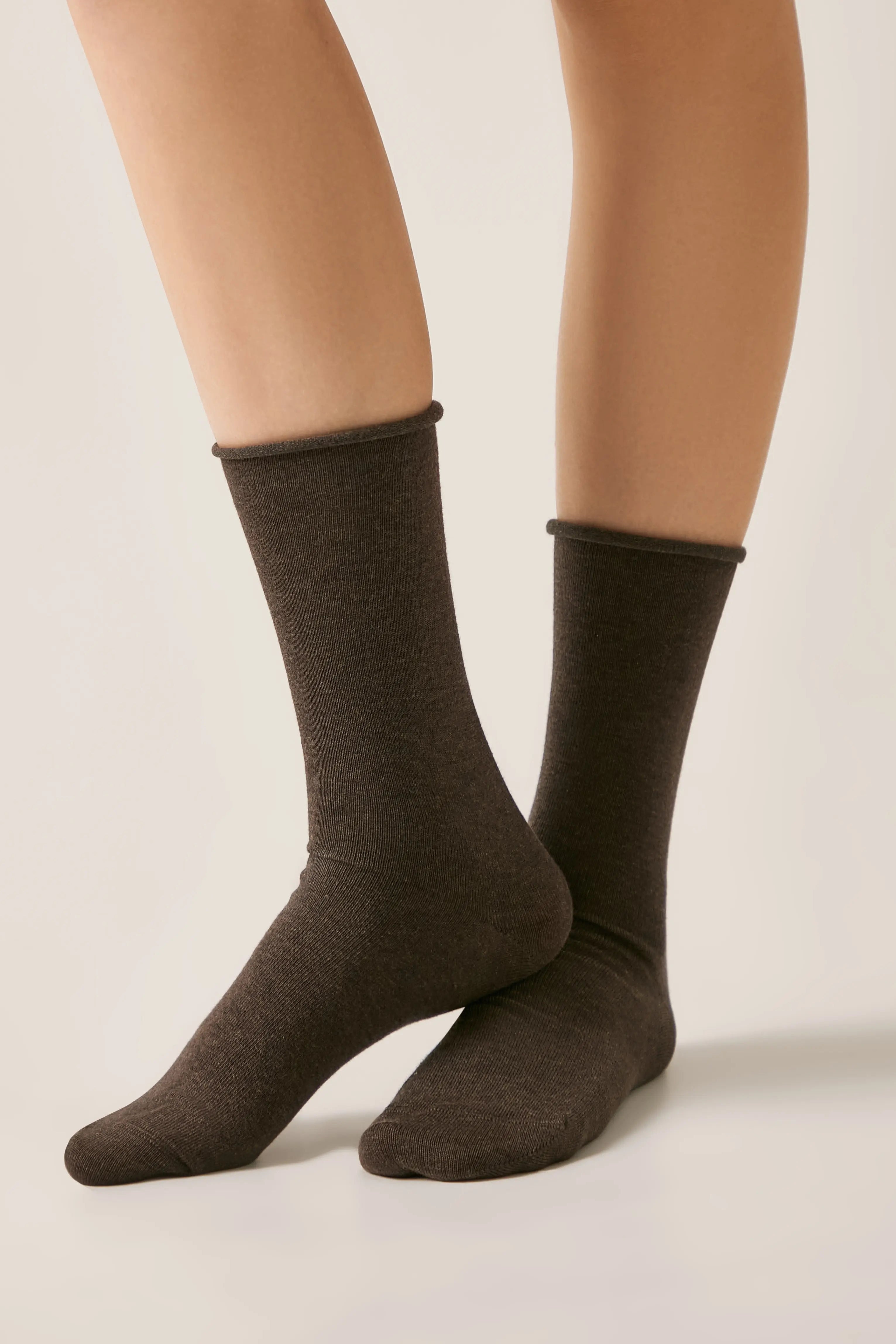 Brown socks worn with beige tights on a neutral background #color_dark-brown