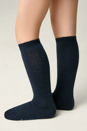 Navy blue knee-high socks worn by a person on a light gray background #color_dark-blue