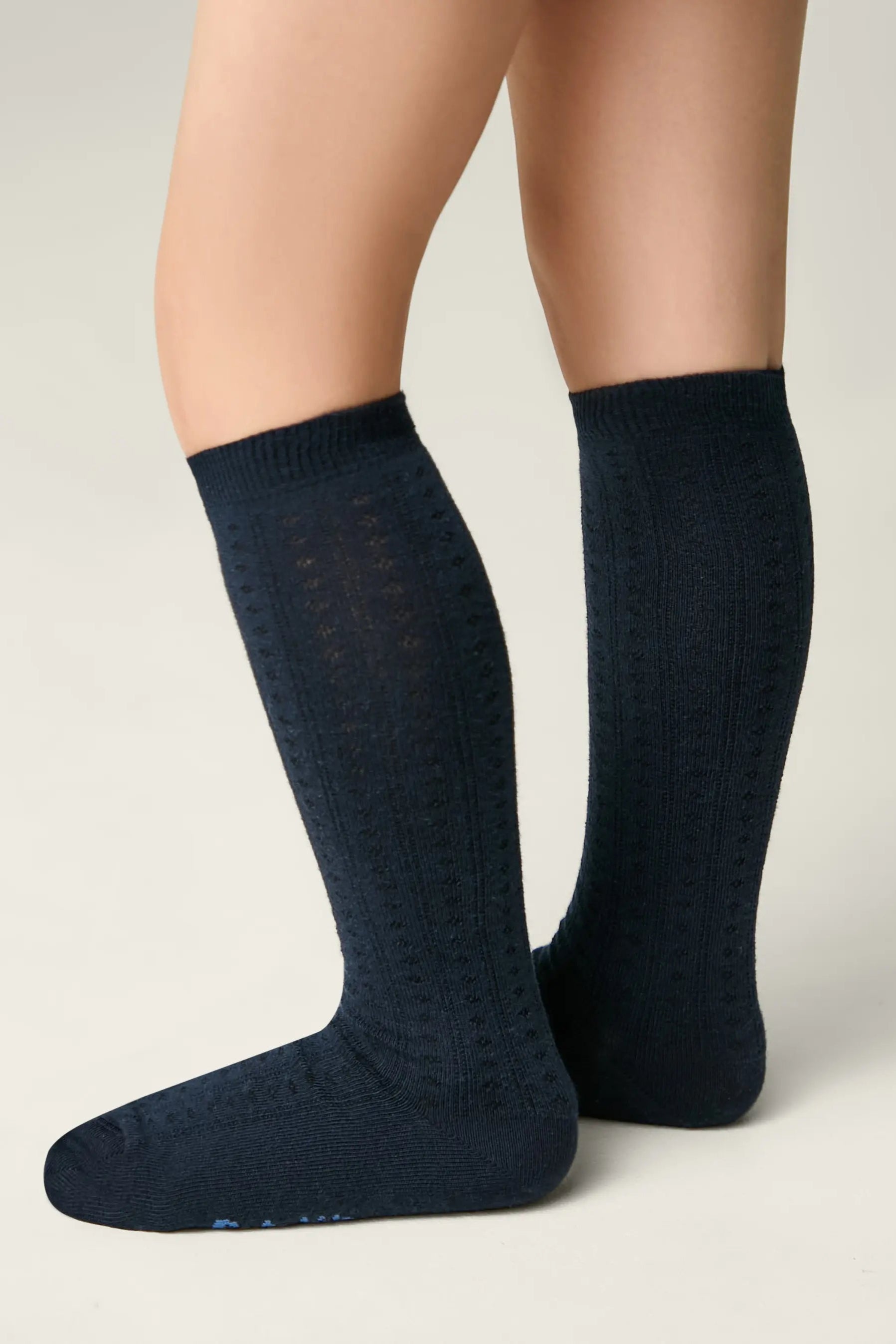 Navy blue knee-high socks worn by a person on a light gray background #color_dark-blue