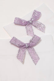 Three purple glittery bows on a white background
