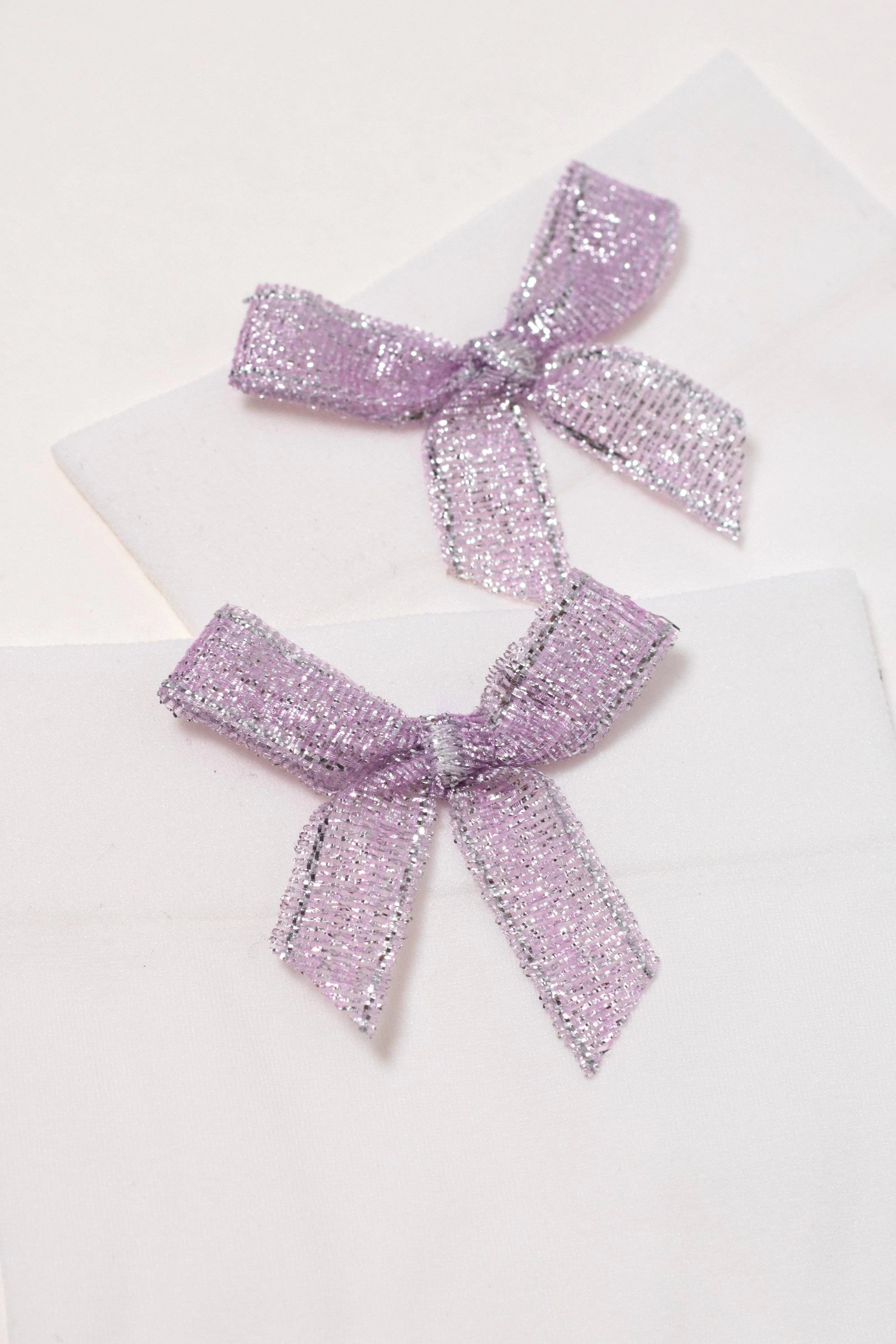 Three purple glittery bows on a white background