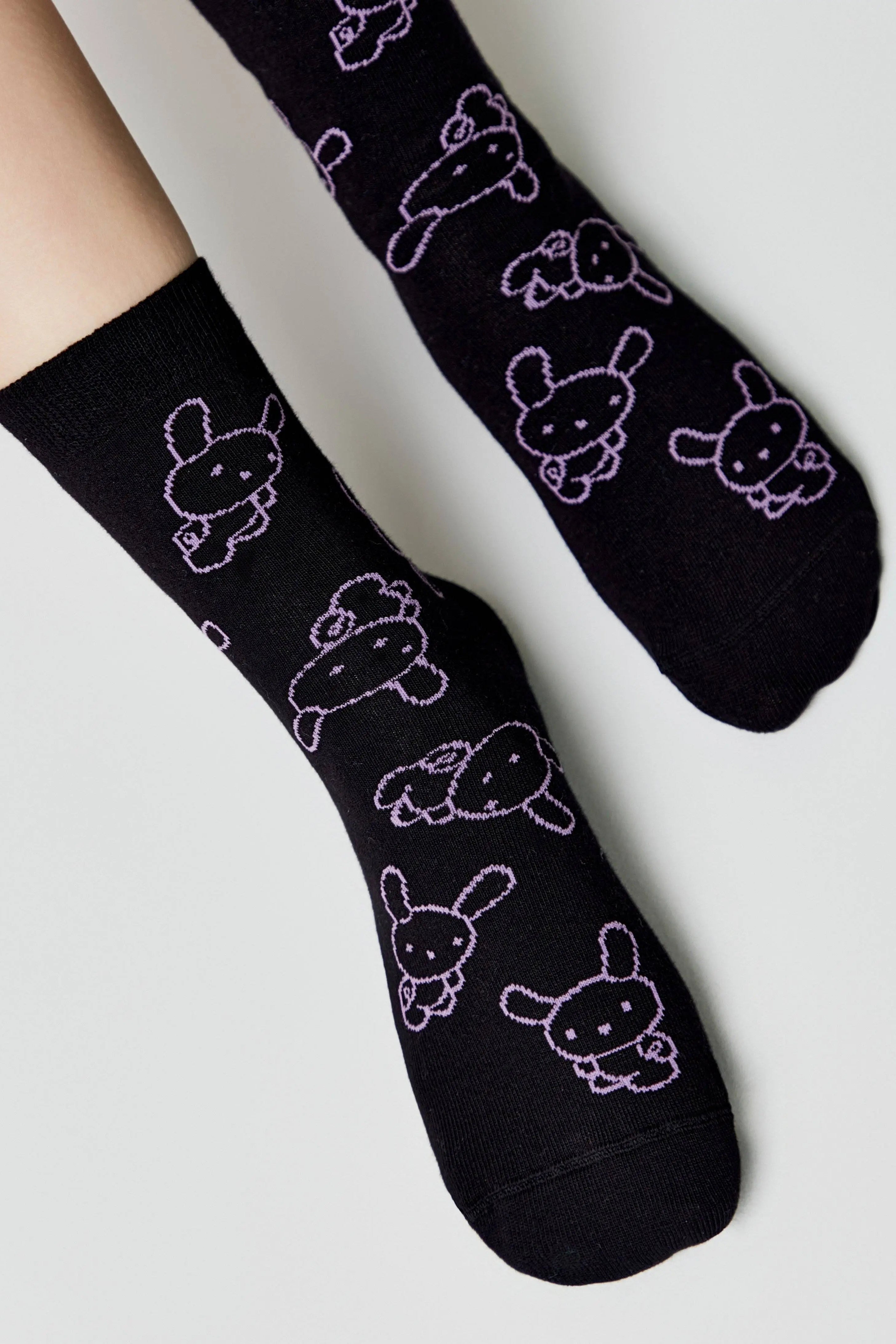 Black socks with white bunny designs on a light gray background