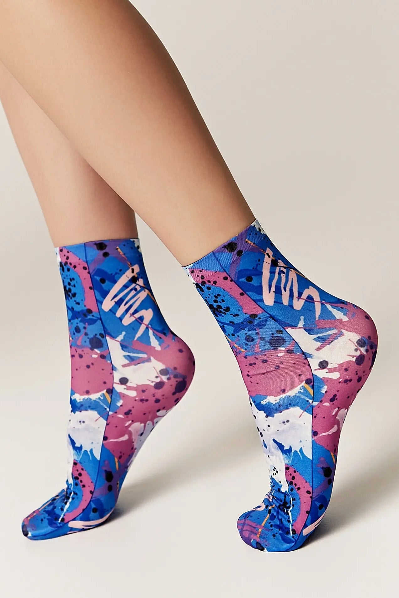 Colorful socks with abstract design worn by a person on a neutral background