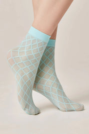 Sheer fishnet socks with a lattice pattern worn by a person on a beige background #color_turquoise