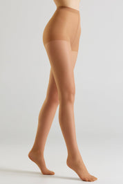 A model's legs wearing sheer, skin-toned hosiery against a clean, light gray studio background.