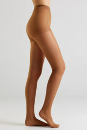 Side view of a model's legs wearing sheer, skin-toned hosiery against a clean, light gray studio background.