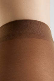 Close-up of a person's leg wearing sheer brown hosiery with a wide ribbed waistband.