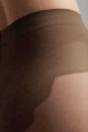 Close-up of a person wearing brown leggings with a textured waistband.