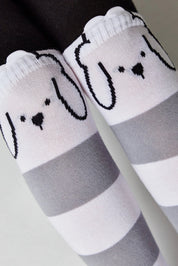 White socks with gray stripes and cartoon dog faces on a neutral background