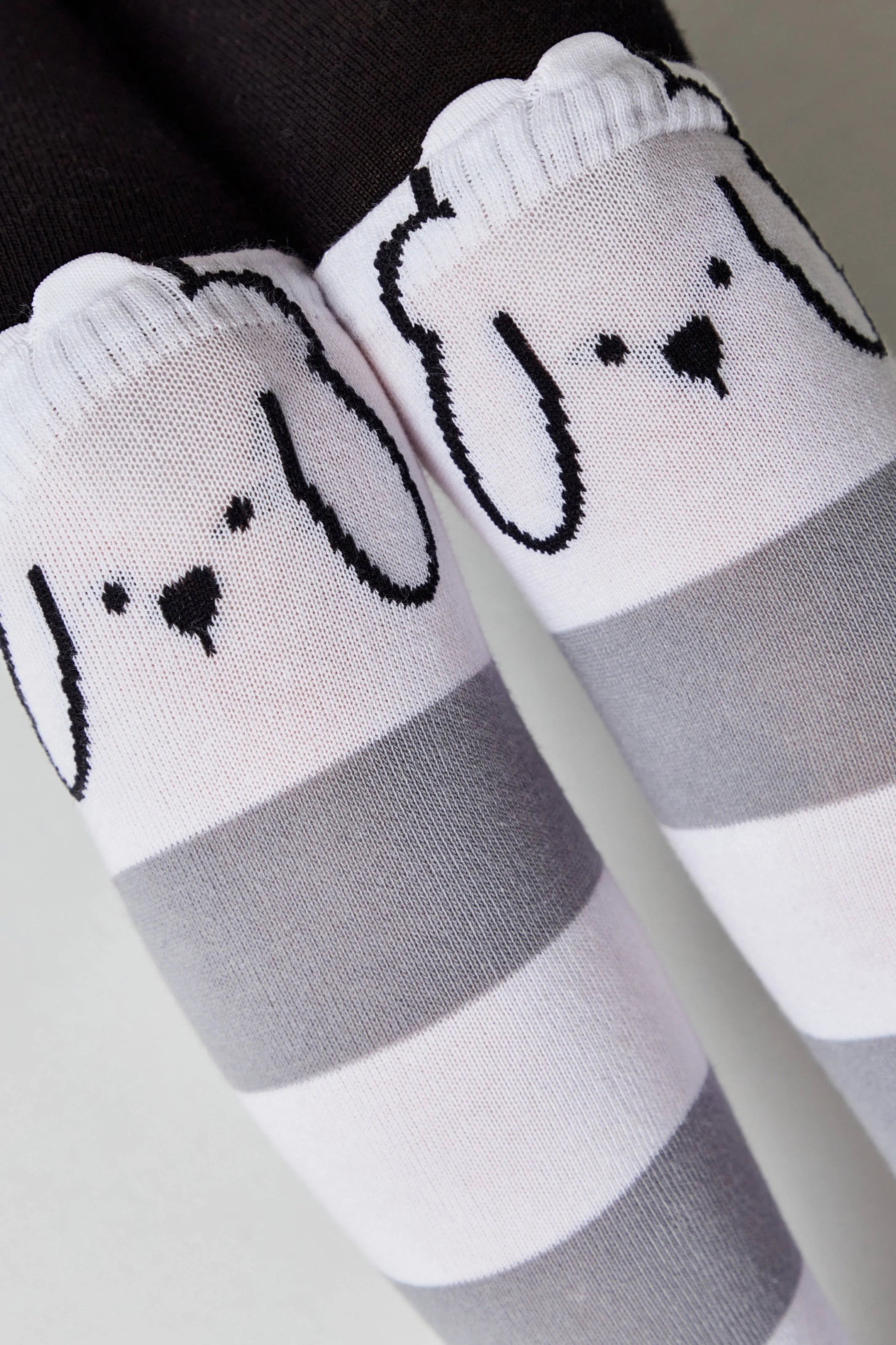 White socks with gray stripes and cartoon dog faces on a neutral background