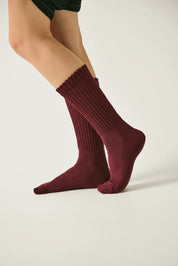 Maroon socks worn by a person on a plain background