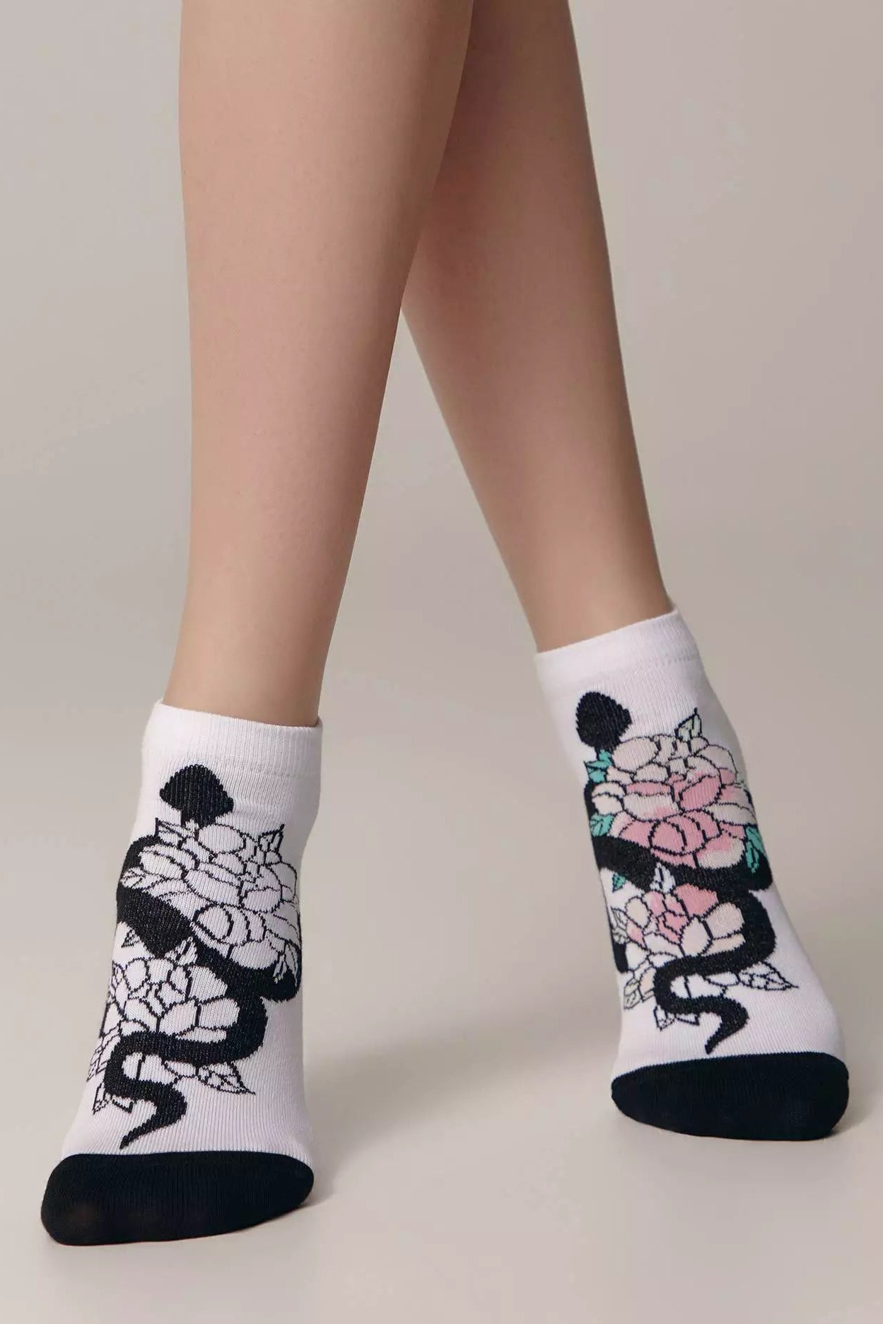 White socks with black floral designs worn by a person on a neutral background