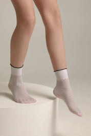 White socks with black dots worn by a person on a neutral background