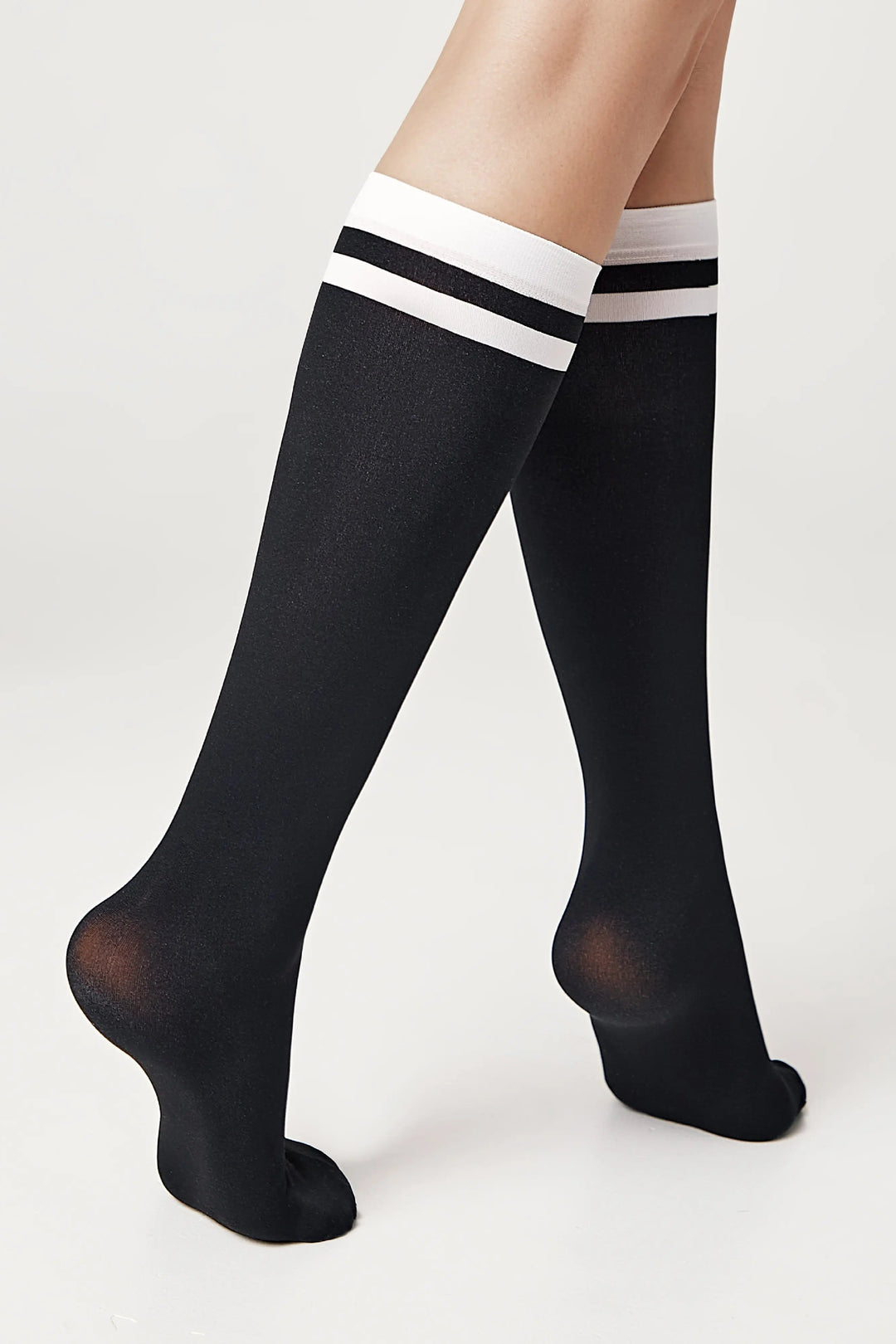 Black knee-high socks with white stripes on a light gray background