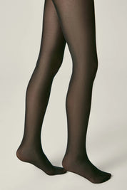 Black tights worn by a person on a beige background #color_nero-black