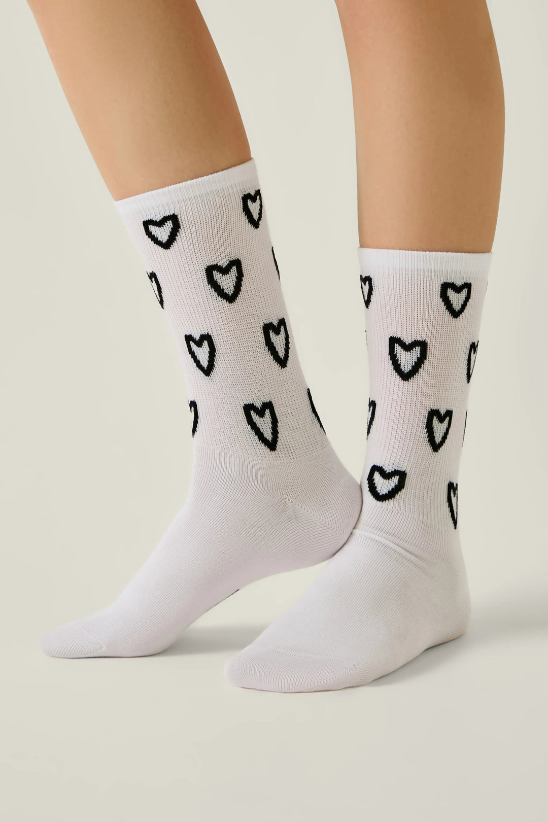 White socks with black heart patterns worn by a person on a light gray background #color_white