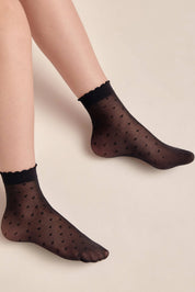 Black polka dot socks worn by a person on a beige background #color_nero-black