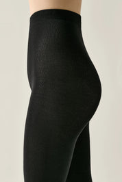 Black tights worn by a person on a beige background