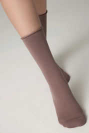Brown knee-high socks worn with beige tights on a plain background #color_cocoa