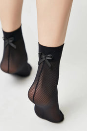 Black fishnet socks with bow details on a light gray background #color_nero-black