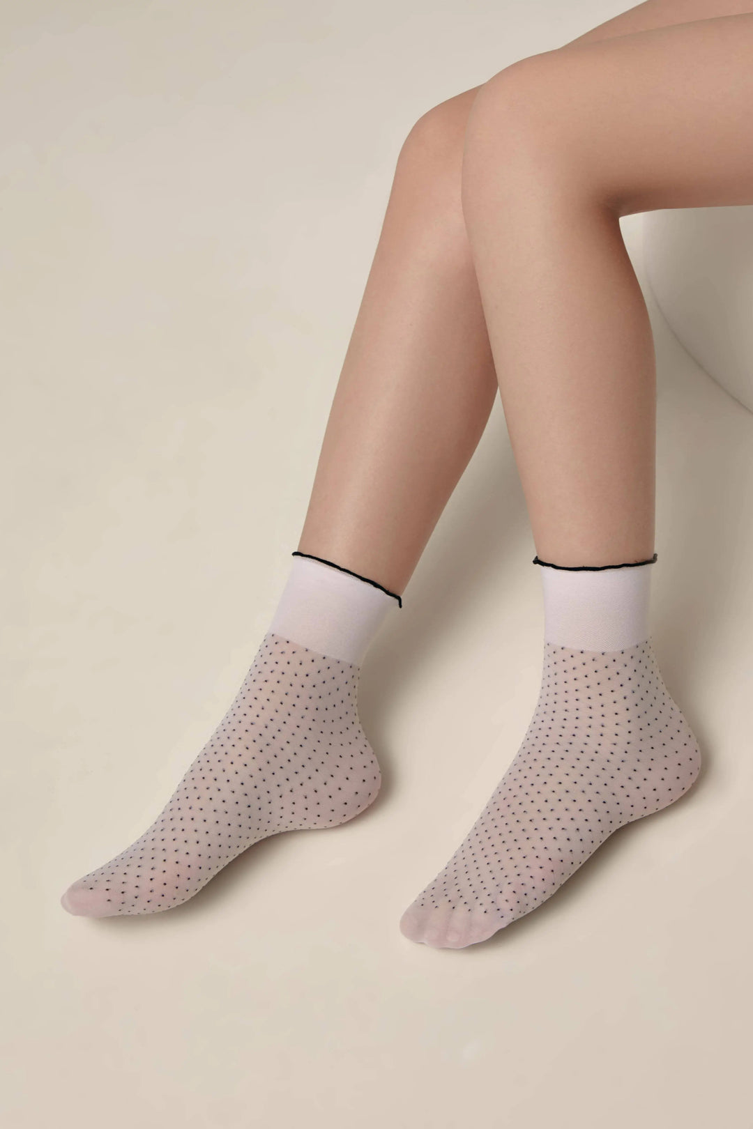 Person wearing light gray socks with a subtle pattern on a beige background