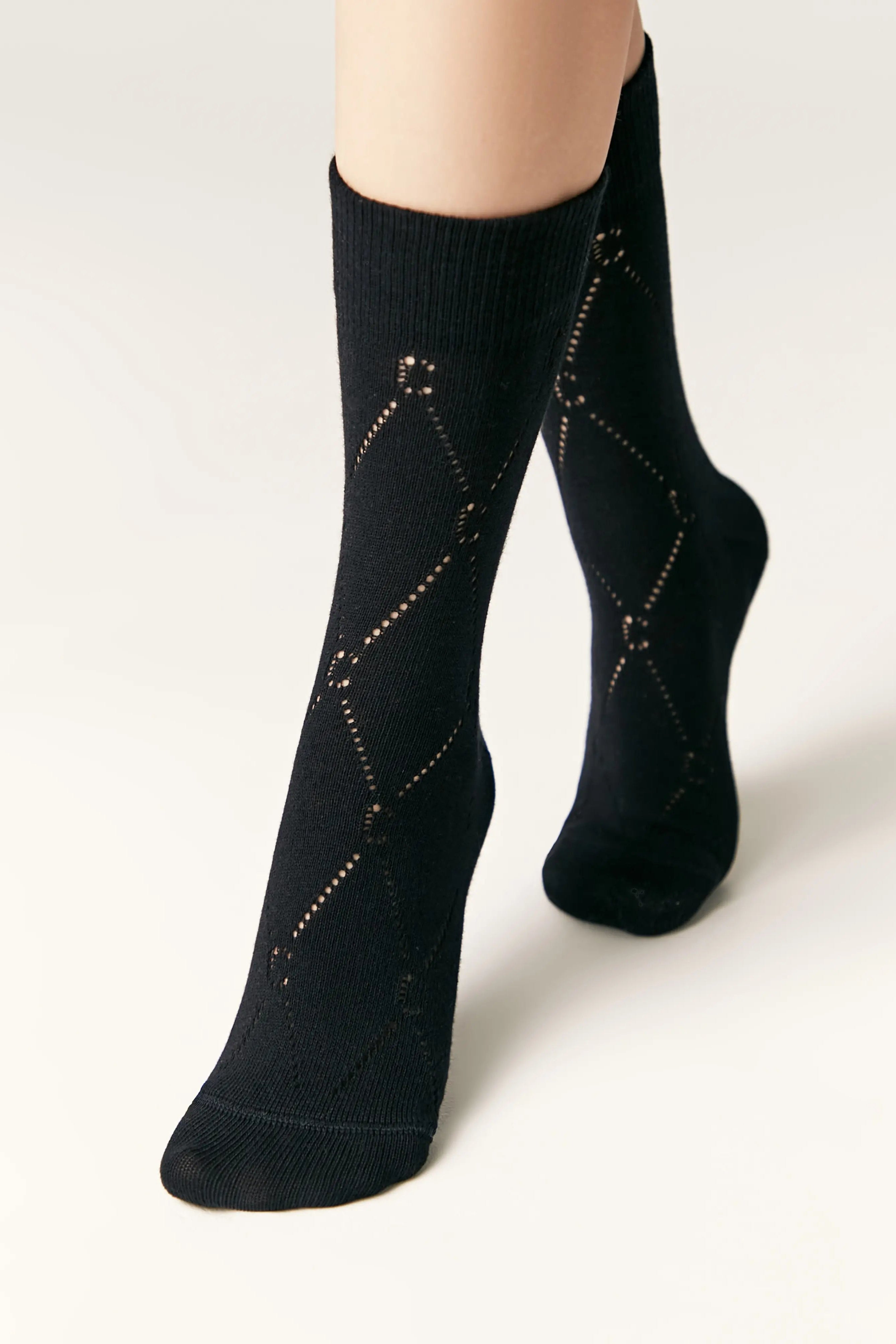 Black socks with diamond pattern worn by a person on a light background #color_black