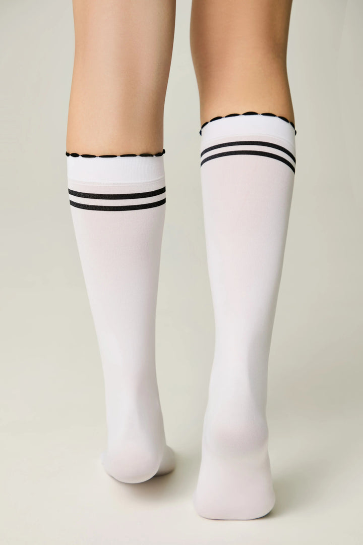 White knee-high socks with black stripes worn by a person on a plain background