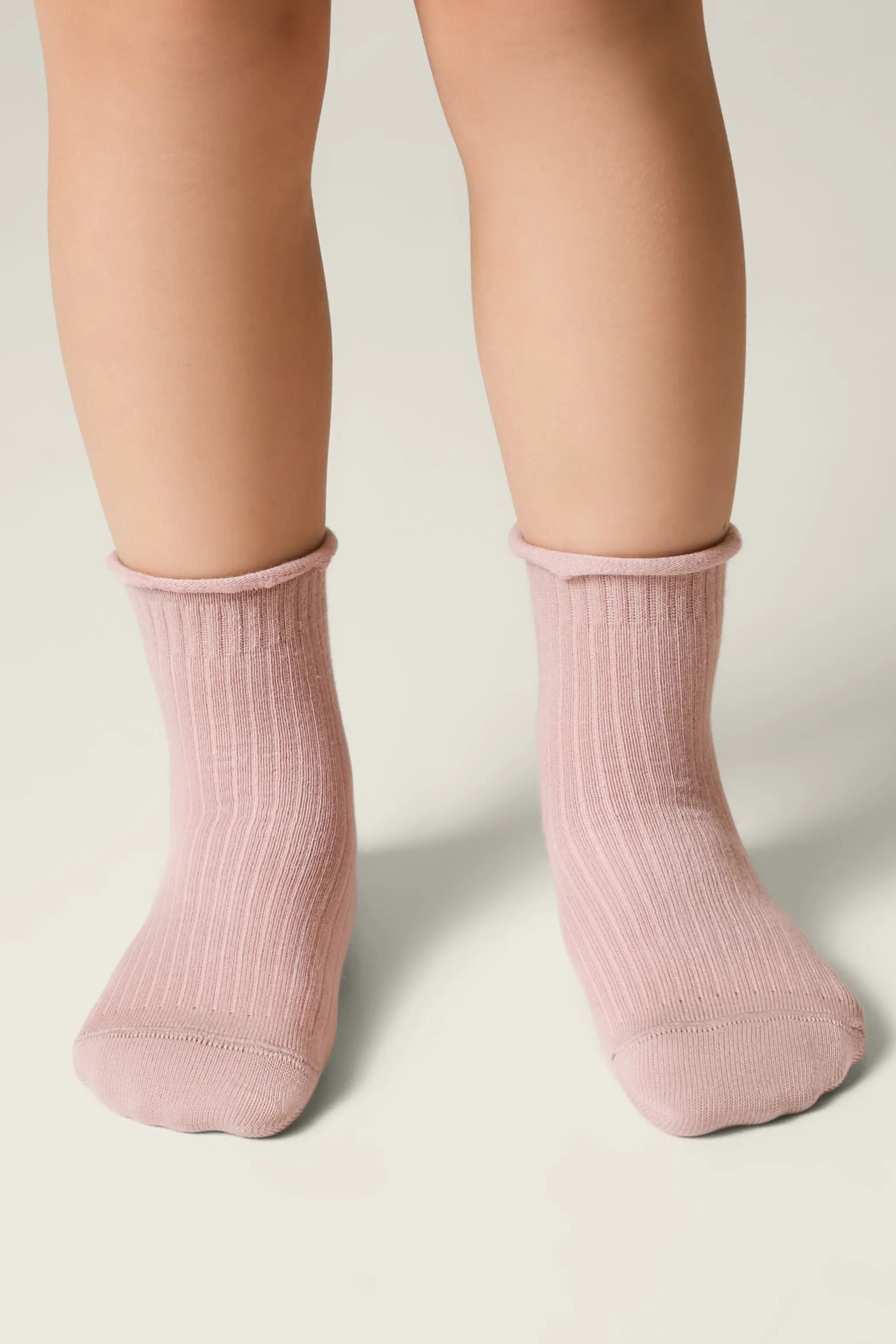 Pink socks worn by a person on a neutral background #color_ash-pink