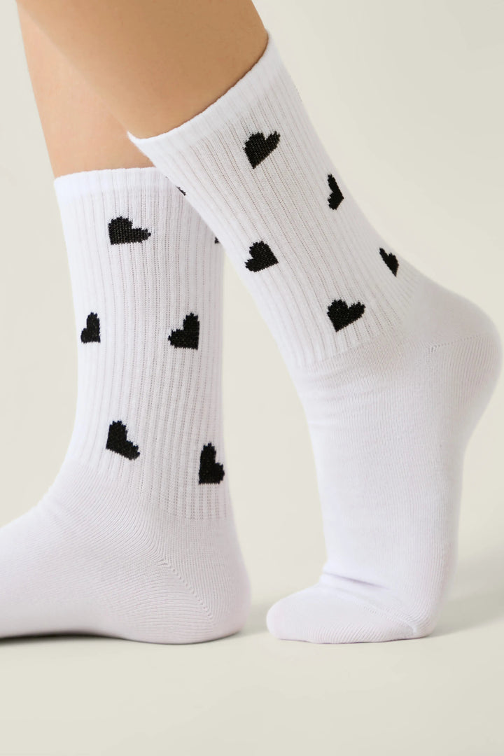 White socks with black heart patterns on a neutral background #color_white