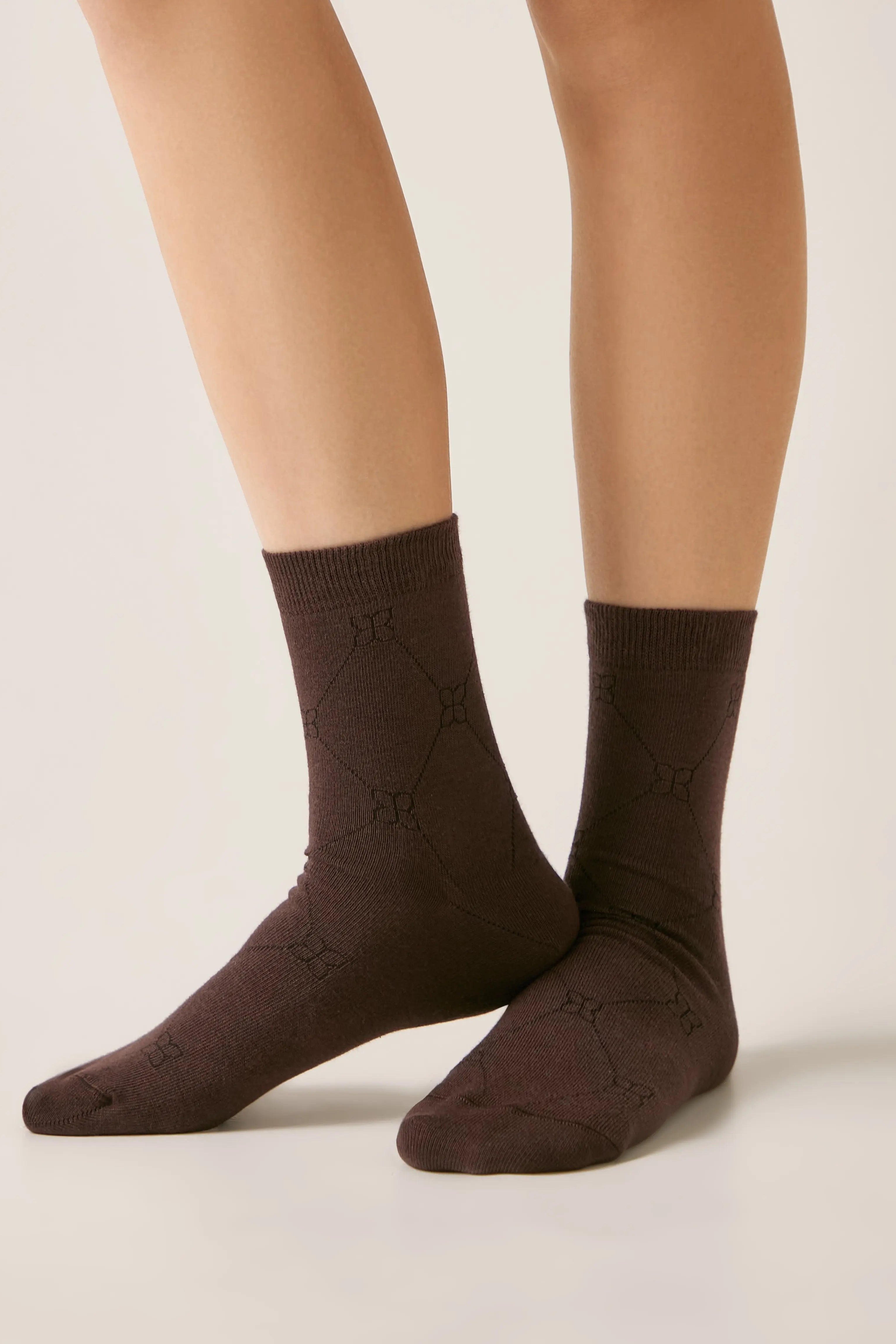 Brown socks worn with beige tights on a neutral background #color_chocolate