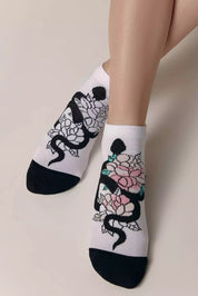 White socks with black snake and floral design on a neutral background