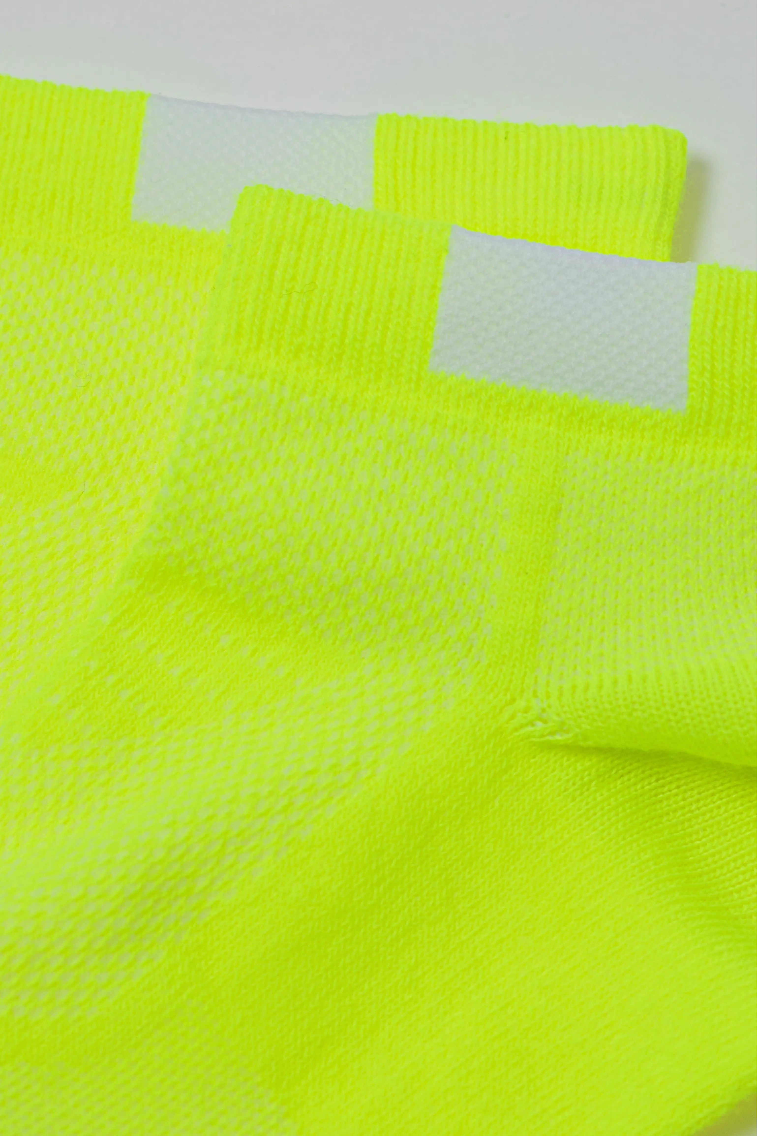 Close-up of bright yellow socks with mesh design on a white background #color_lime-green