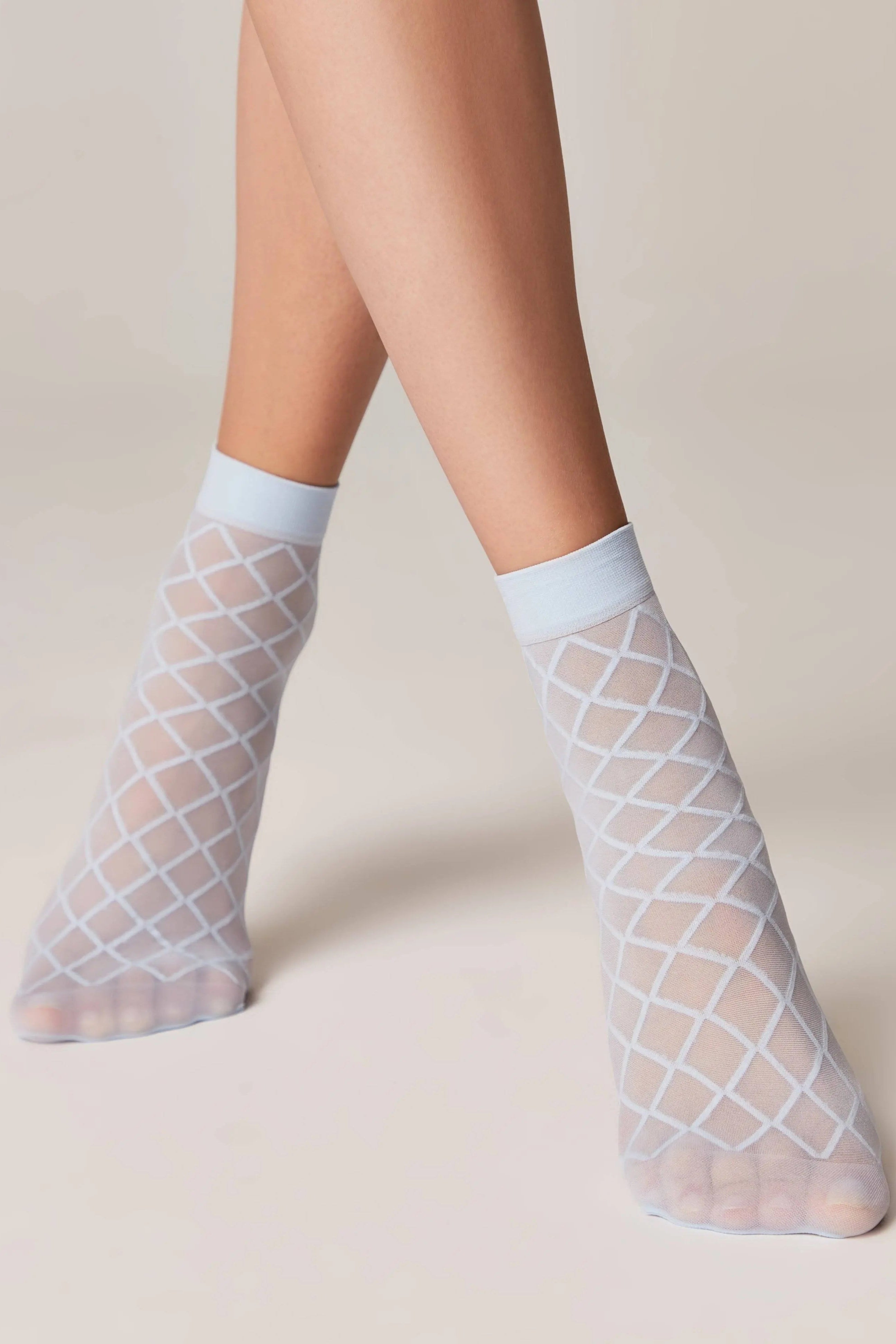 Sheer fishnet socks with grid pattern worn by a person on a neutral background #color_light-blue