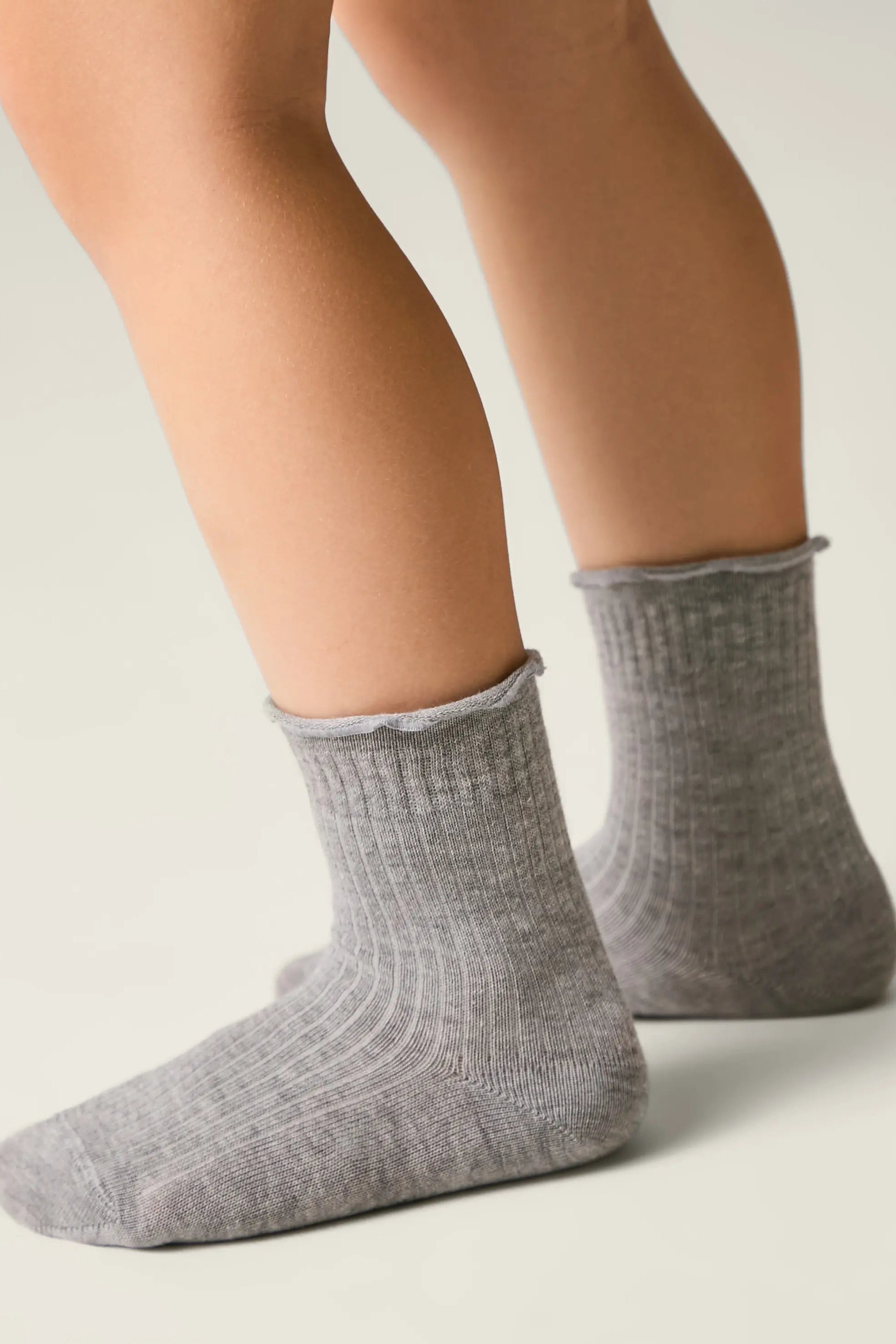 Gray socks worn by a person on a light background #color_gray
