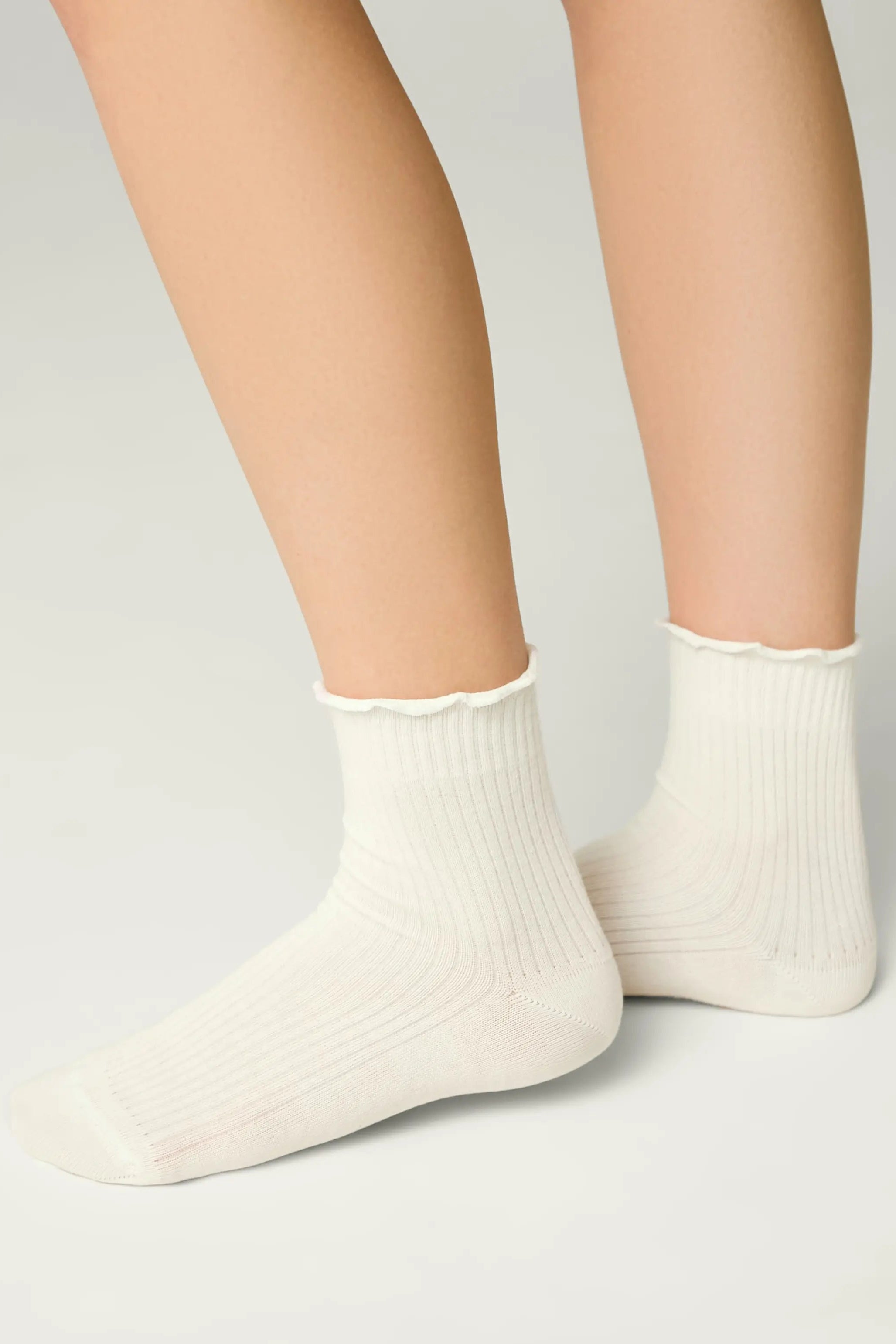White socks worn by a person on a light gray background #color_milky