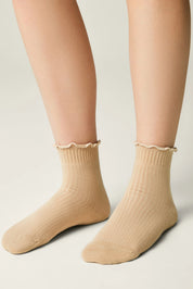 Beige socks with ruffled top worn by a person on a light gray background #color_beige
