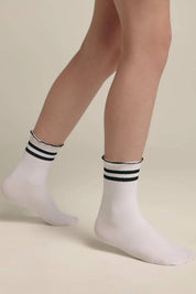 White socks with black stripes worn by a person on a beige background