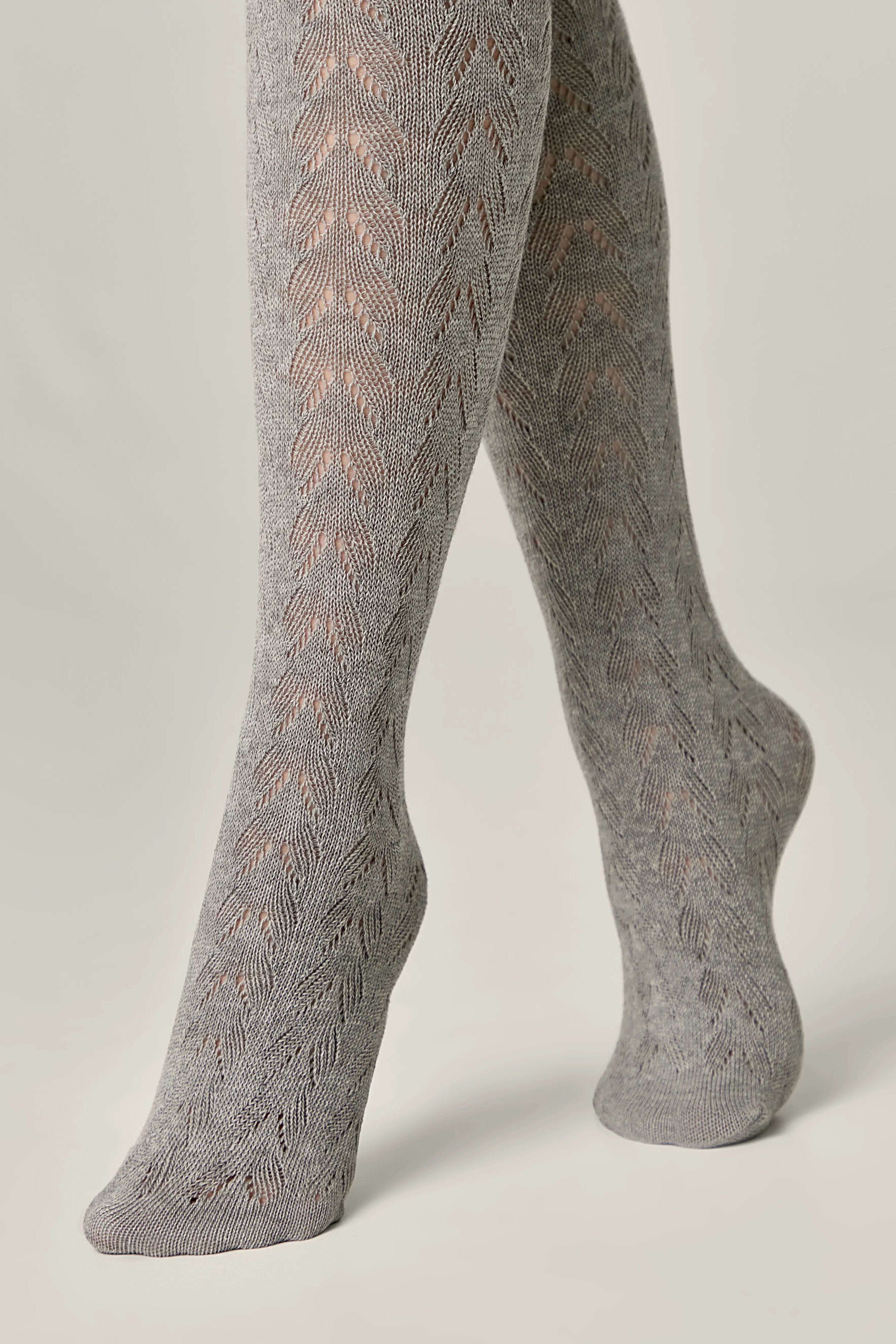Gray patterned tights worn by a person on a light gray background #color_grey
