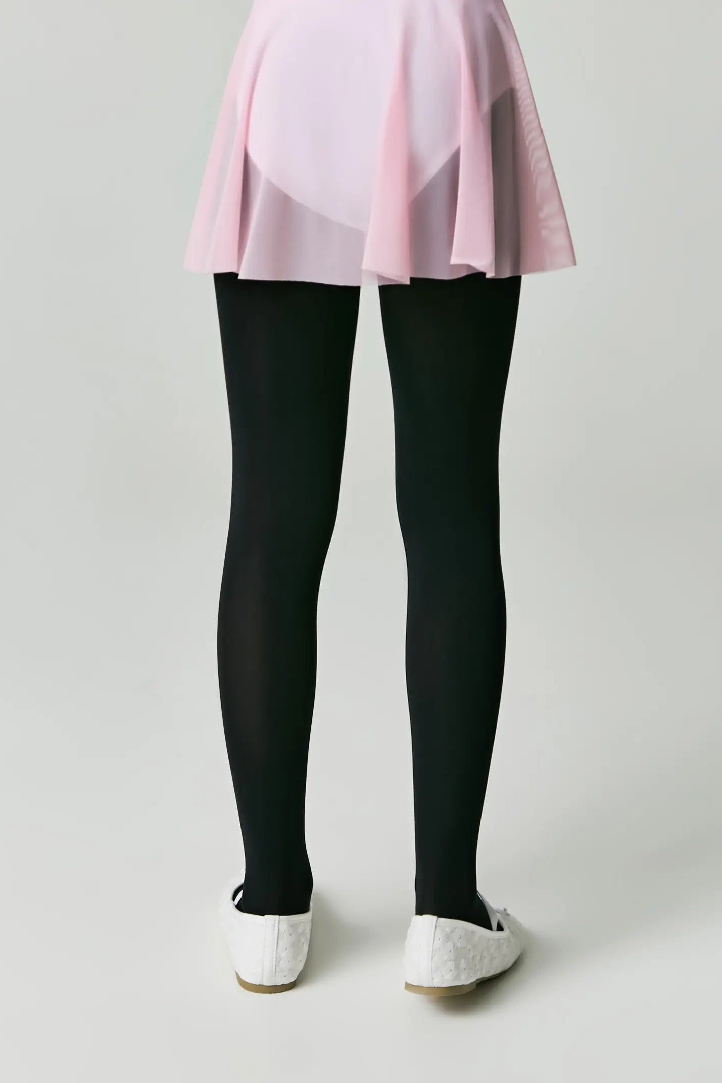 Person wearing a pink top and black leggings on a plain background #color_nero-black